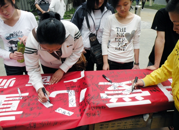 我校志愿者在爱心横幅上签名。