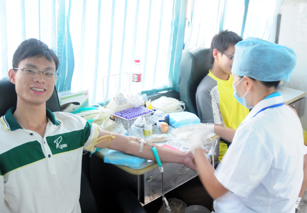 献血车上，我校学生在愉快地献血。