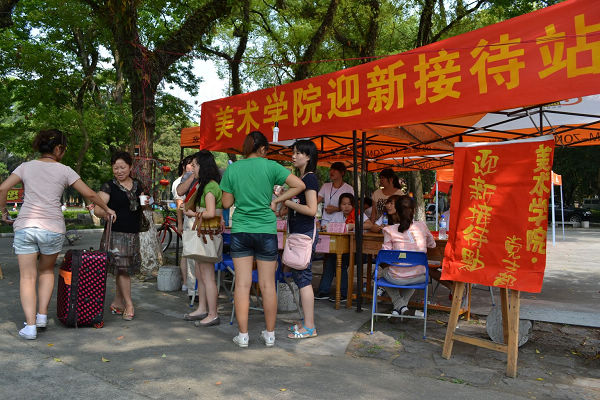 王城校区的迎新接待站里，美术学院学生党员帮新生及其家长搬运行李（大学生记者团 唐辉林 摄）