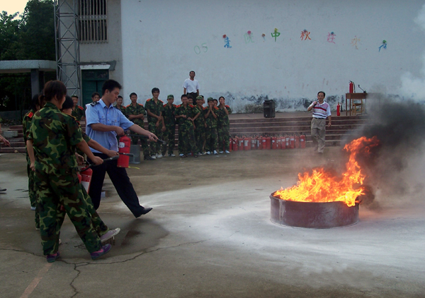 校保卫处的同志正在指导新生们进行现场消防演习。