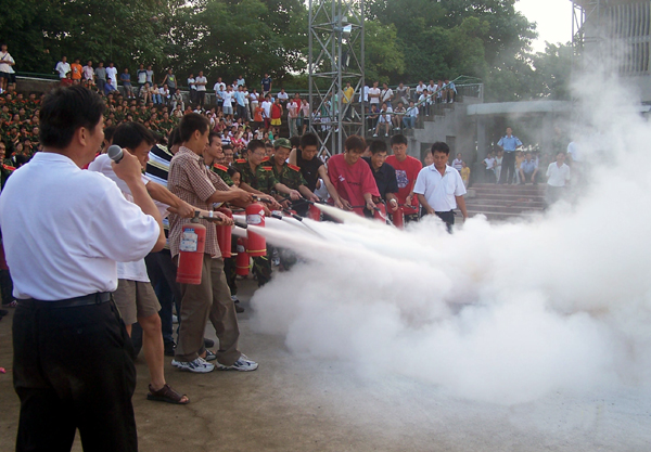 校保卫处的同志指导新生们进行现场消防演习。