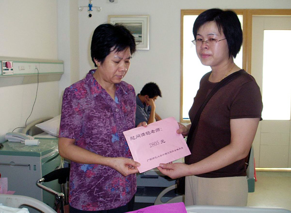 我校“巾帼文明岗”岗员代表把爱心款交到谭妈妈手上。