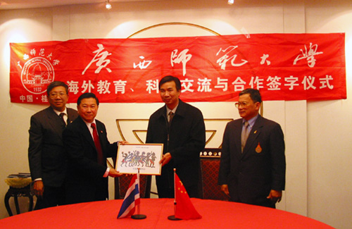 图为我校梁宏校长（右二）接受泰国客人赠与的泰国彩绘图。