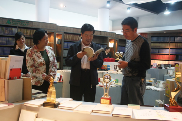 自治区政协主席马铁山(右二)在饶有兴致地翻看校出版社的图书。(出版社 郭展炜)