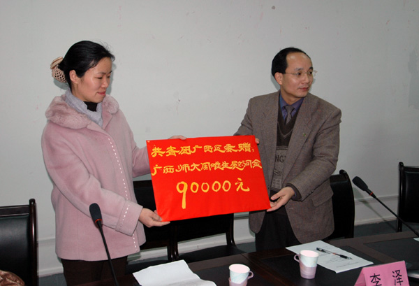 我校党委副书记林娜（左）从团区委副书记李泽手中接过团区委发放给我校留校过年困难学生的9万元慰问金。