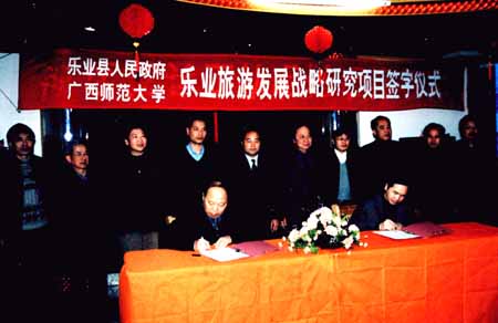 图为我校党委副书记、旅游研究所所长阳国亮（左）与乐业县县长周武红分别在协议上签字。