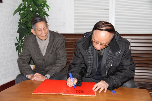 裴大使(右)在越南学校纪念馆留言簿上留言