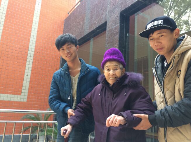 桂林市夕阳红养老院内美术学院志愿者同学们搀扶老人