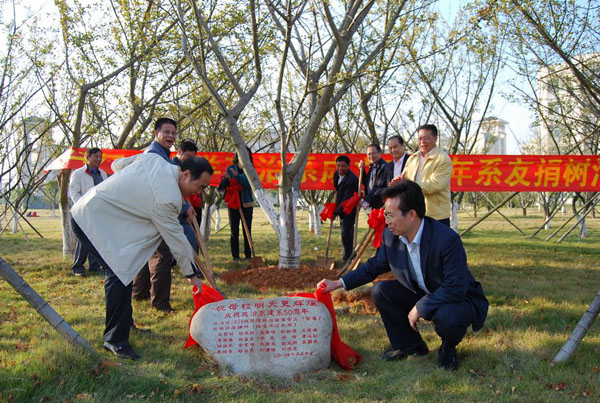 校友总会负责人（右）与校友在政治系1986级系友捐种的爱心树下为纪念石揭幕