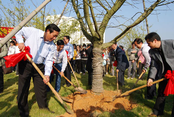 陈洪江副校长（左）与系友一起为爱心树培土