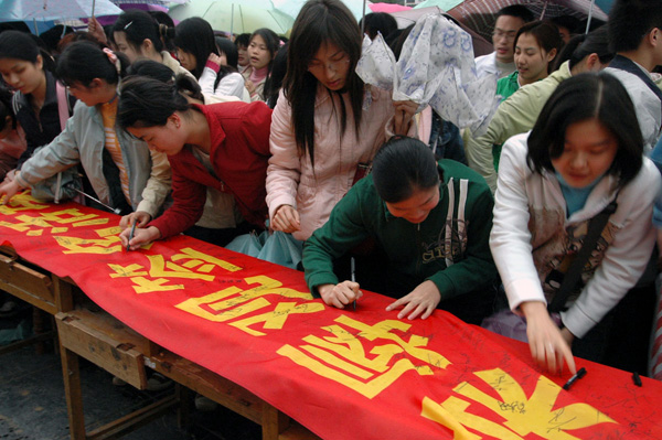 我校学生在巨幅横幅上签名。