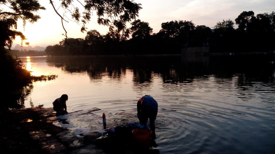 落日下村民浣衣的背影