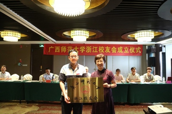 学校总会计师、校友总会常务副会长丁静（左）与绍兴奥德赛电器有限公司总经理、浙江校友会会长、物理系93级本科班李健校友（右）授牌