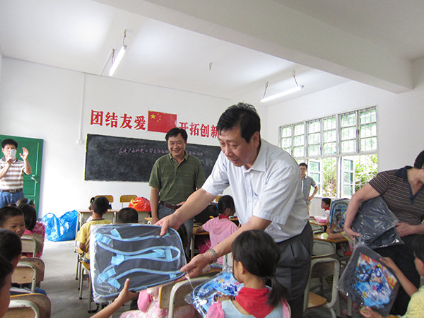 民进我校支部成员、副校长陈洪江向同学们赠送书包