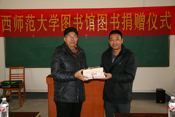我校图书馆馆长代表赠书师生将赠书交到朝板山初中校长手中