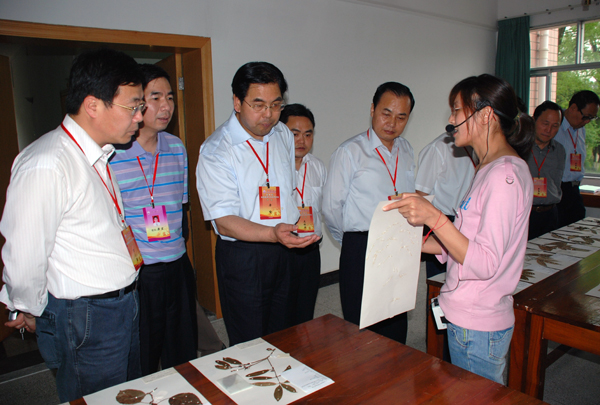 评估专家在我校实习实训基地雁山植物园标本室听取我校学生介绍植物标本。