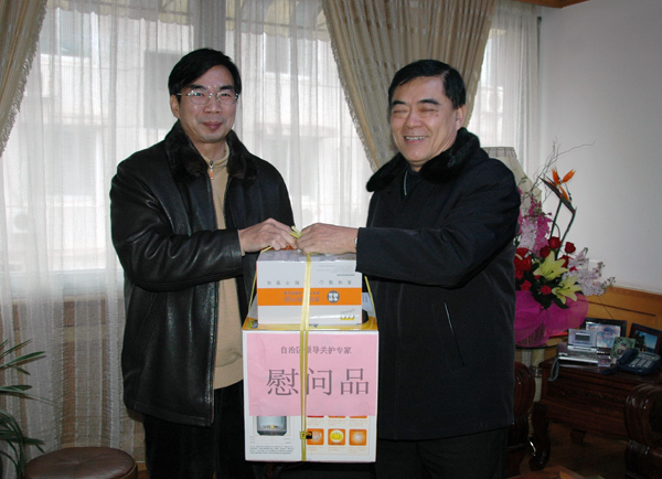 桂林市政协主席李文杰（右）代表自治区向梁宏教授送上慰问品。