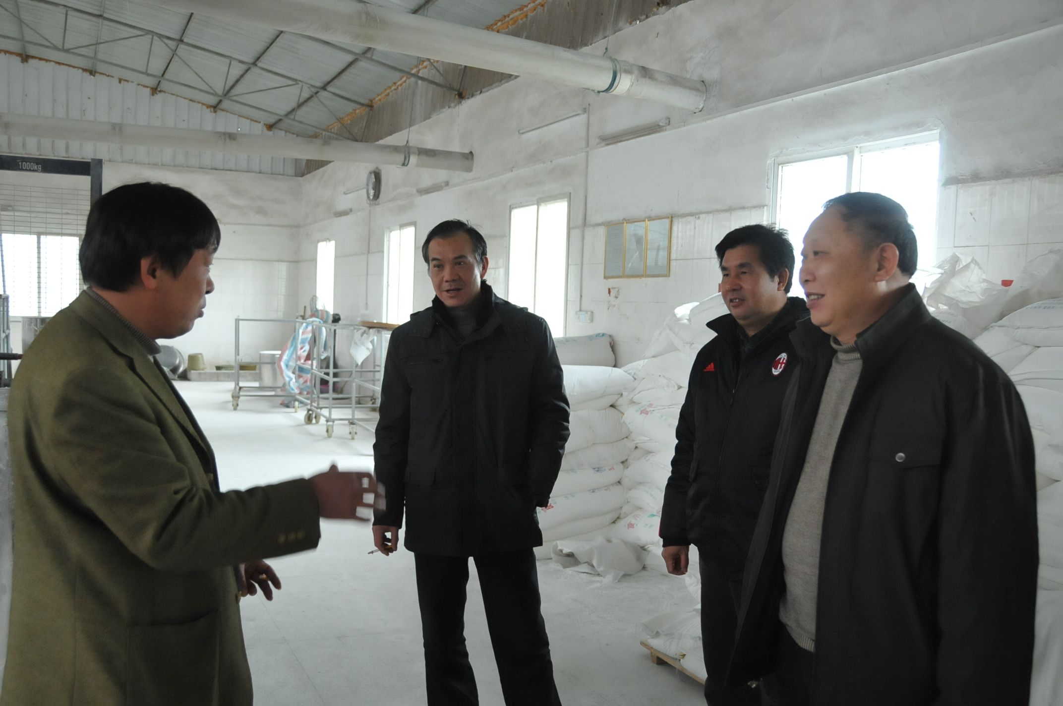 创业职工王严(左)向刘健斌副校长一行介绍米粉生产流程