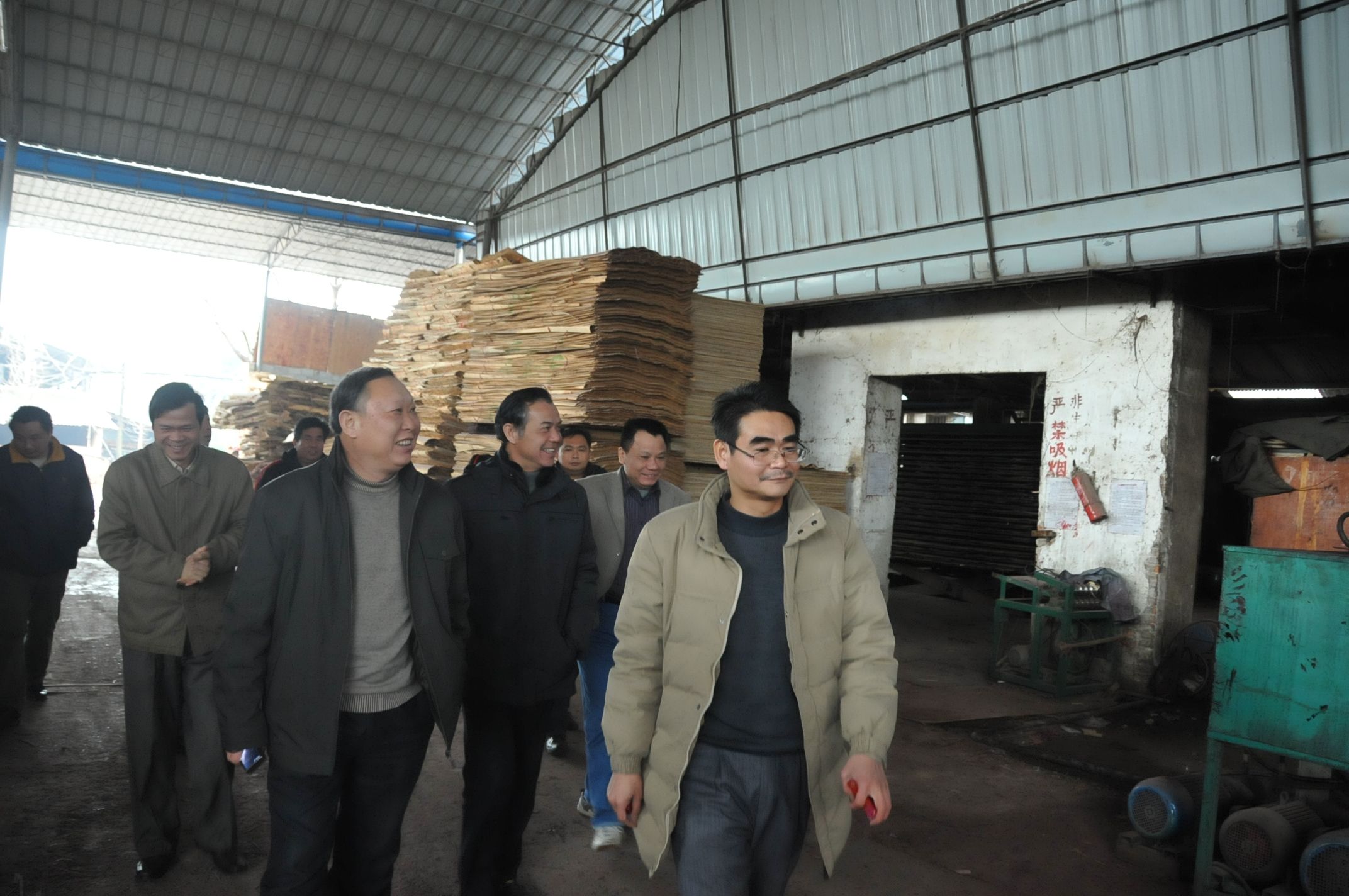 创业职工肖贵寿（右前）带领刘健斌副校长一行参观厂房