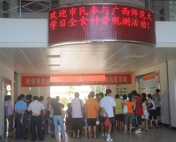 师生和市民在物理与科学技术学院实验中心一楼大厅观看电视直播效果。