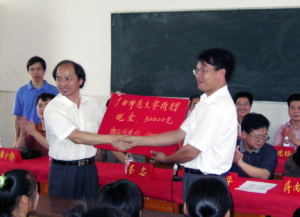 易忠副校长（左）把我校捐赠的3万元现金交到思恩中学韦继祖校长手中