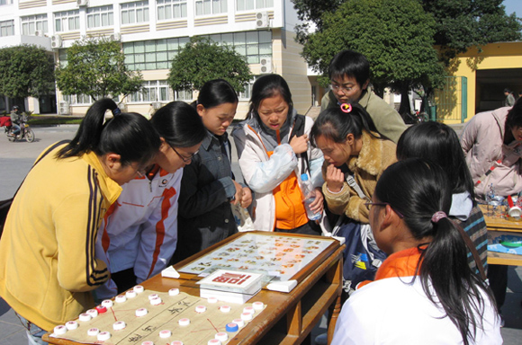 同学们在手工制作品展览现场参观手工制作的中国象棋和北京奥运福娃。