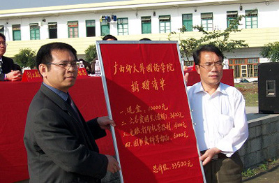 思恩中学校长从我校外国语学院领导手中接过捐赠的款物。