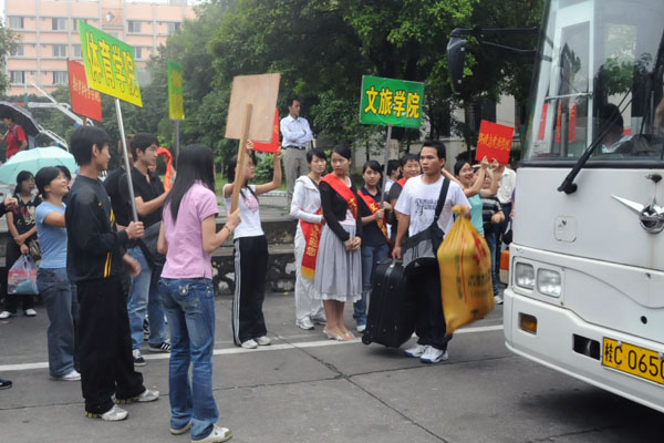 各学院接待点的同学在校车前迎候从火车站接来的新生。